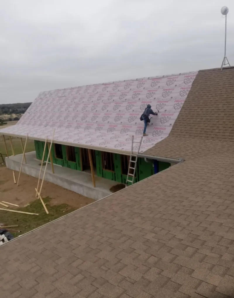 Worker preparing underlayment for a metal roof installation in Rantoul